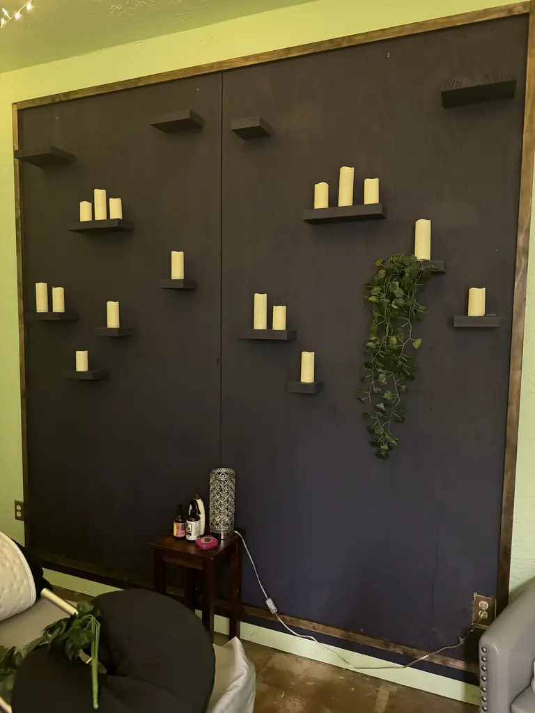 Candles glowing on floating shelves along a dark wall with trailing greenery
