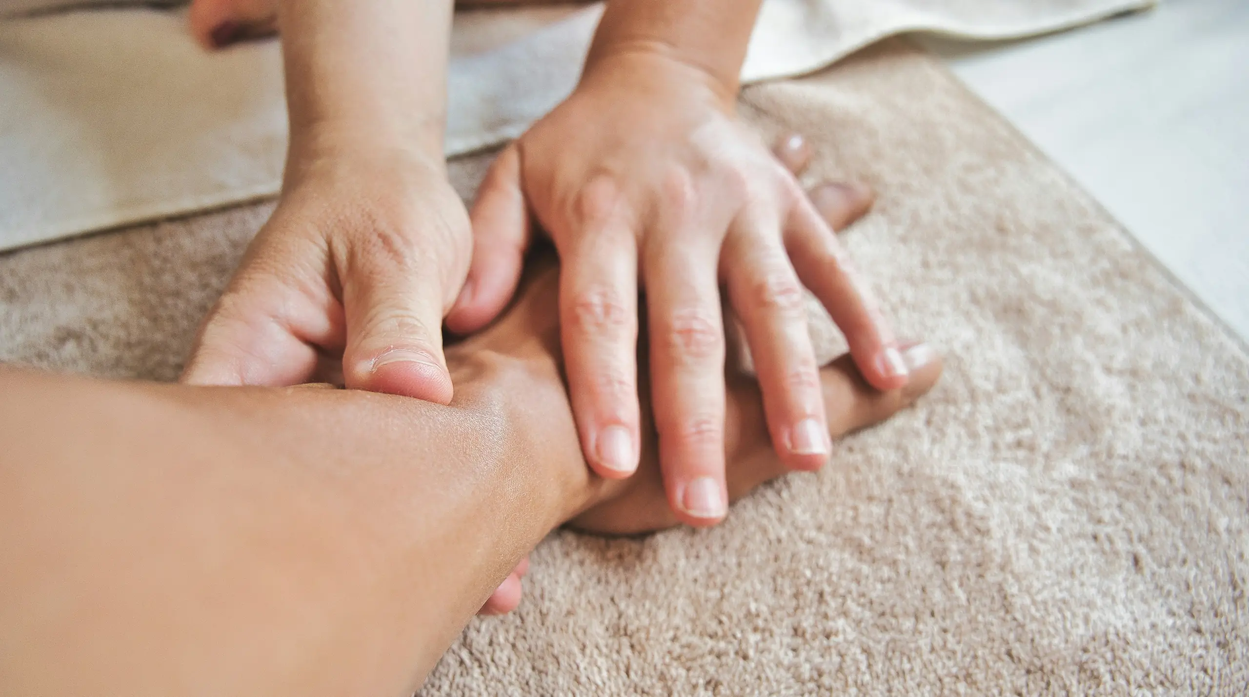 A massage therapist working slow, firm pressure into a client's arm
